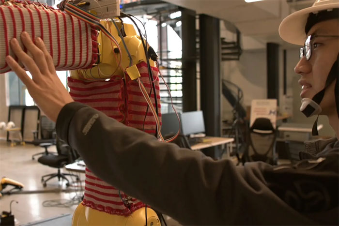 Bộ quần áo được quấn quanh cánh tay robot và được kết nối với nguồn điện.