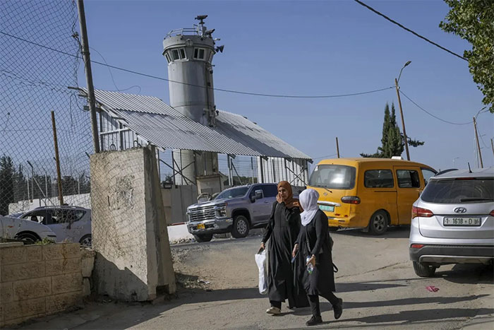  Hai người Palestine đang đi bộ ngang qua tháp canh quân sự nói trên của Israel. 