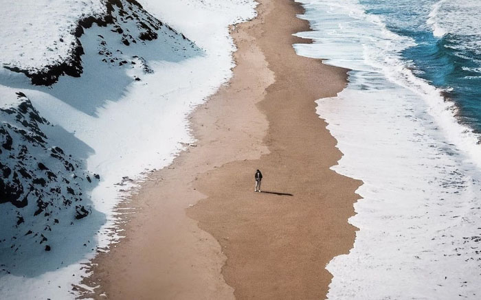 Hình ảnh của một bãi biển, một bên là tuyết, một bên là biển và ở giữa là một bãi cát vàng.